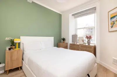 a bedroom with a white bed and a window at Elegant Apartment in the heart of Edinburgh in Edinburgh