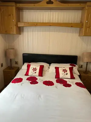 a bed with red roses on it with two pillows at 77 Glenfinart Caravan Park in Dunoon
