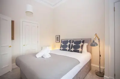 a bedroom with a large bed with a lamp at Spacious Period Property in Glasgow in Glasgow