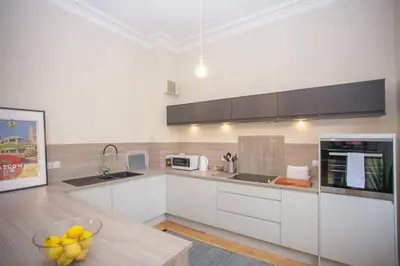 a kitchen with white cabinets and a bowl of fruit on a table at Spacious Period Property in Glasgow in Glasgow