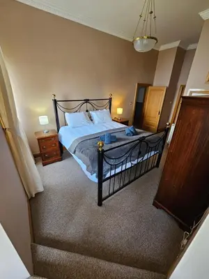 a bedroom with a bed with white sheets and a staircase at No 8 Lomond Castle in Luss