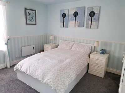a bedroom with a white bed and two night stands at Historic central apartment in Castlehill Mansions in Campbeltown