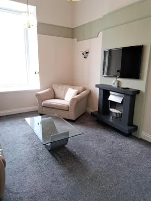 a living room with a couch and a television at Historic central apartment in Castlehill Mansions in Campbeltown