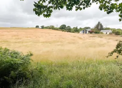 a field of grass with a house in the distance at 5 Bed Family Home Lochwinnoch in Lochwinnoch