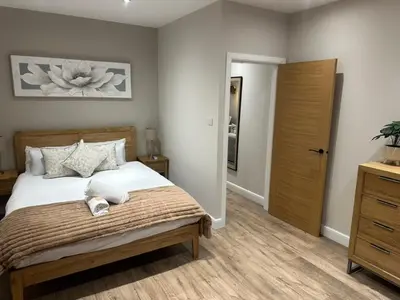 a bedroom with a large bed and a wooden closet at BOFA Snug Apartment in Bridge of Allan