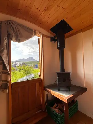 a wood stove in a room with a window at The Shepherd's Hut in Craighouse