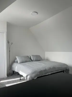 a bed in a room with a white wall at Upper Mill Apartment in Newmilns