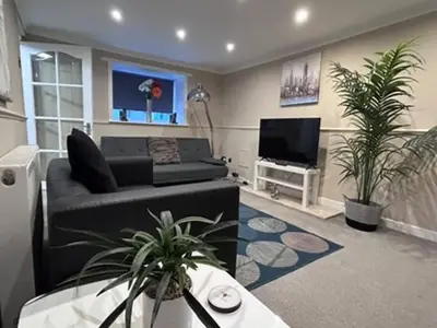 a living room with a couch and two potted plants at Abbeygreen Village House in Lesmahagow