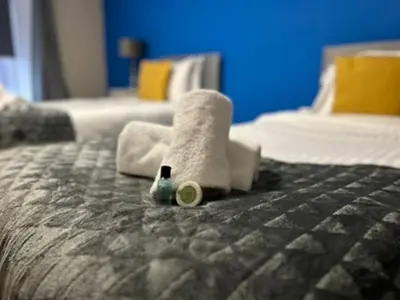 a hotel room with towels and a bottle on a bed at Abbeygreen Village House in Lesmahagow