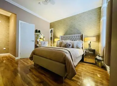 a bedroom with a large bed and a wooden floor at Isle Be Back-Ground Floor Flat in Millport