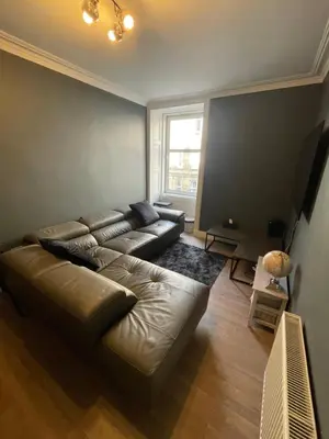 a living room with a leather couch and a window at Fountain park get away one bedroom in a 2 bedroom apartment in Edinburgh