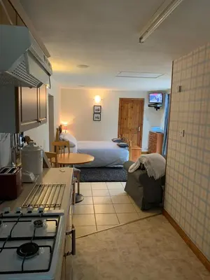 a kitchen with a stove and a bed in a room at Whitestone Cottage in Turnberry