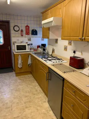 a kitchen with wooden cabinets and a stove top oven at Whitestone Cottage in Turnberry