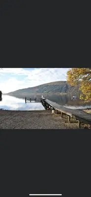 a dock on a lake with a hill in the background at Rowardennan Rooms in the lodge Lodge no 2 in Rowardennan