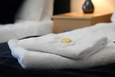 a stack of towels sitting on top of a bed at Townhead Apartments Glasgow Airport in Paisley