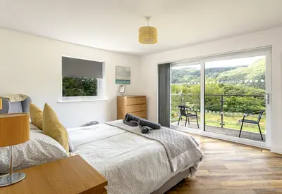 a bedroom with a bed and a sliding glass door at Dalnahua on 'The Secret Coast'