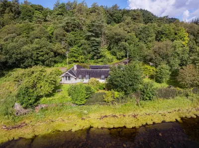an aerial view of a house on a hill next to the water at Castle Cottage No 2 in Acharn