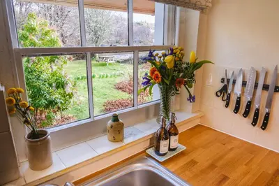a kitchen window with a vase of flowers on a counter at Castle Cottage No 2 in Acharn