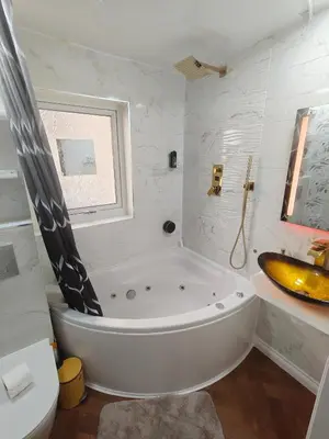a white bathroom with a tub and a sink at Modern Ground Level Flat in Clydebank