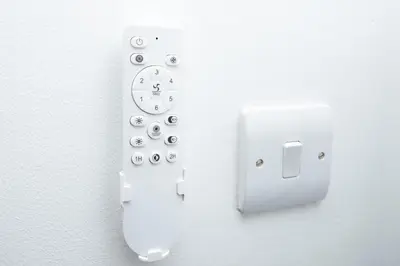 a white remote control with a clock on a wall at Private Home North of Dunblane in Braco