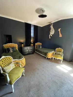 a bedroom with two beds and two chairs at The Old Church Isle of Bute in Port Bannatyne