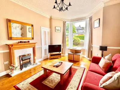 a living room with a red couch and a fireplace at Hide-a-While in Rothesay