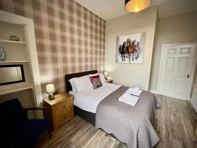 a small bedroom with a bed and a chair at Hide-a-While in Rothesay