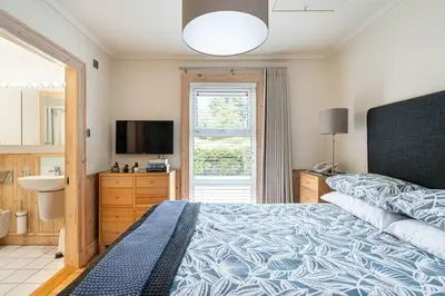 a bedroom with a large bed and a television at Little Juniper Lodge in Edinburgh