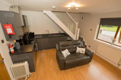 a living room with a chair and a kitchen at Tigh Na Cille Studio in Taynuilt
