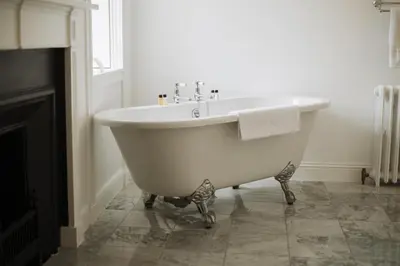 a white bath tub in a bathroom with a fireplace at Islay House in Bridgend