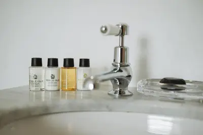 a bathroom sink with four bottles of moisturizers on it at Islay House in Bridgend