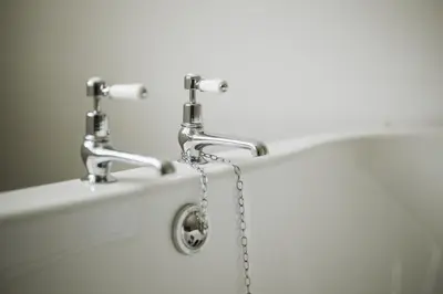 a bath tub with two faucets and a chain at Islay House in Bridgend