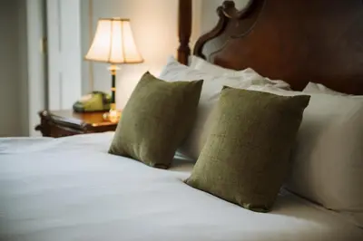a bed with two pillows and a table with a lamp at Islay House in Bridgend