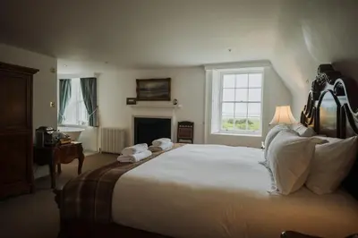 a bedroom with a large white bed and a fireplace at Islay House in Bridgend