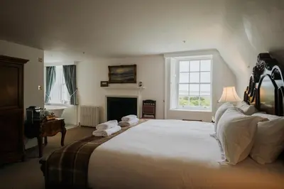 a bedroom with a large white bed with a fireplace at Islay House in Bridgend