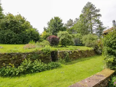 a garden with a stone wall at Townhead of Auchenbainzie in Thornhill