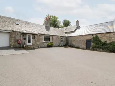 an empty driveway in front of a stone house at Marshill Farm House in Lanark
