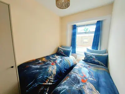 a bedroom with two twin beds next to a window at The Puffins - Largs 2-Bedroom Ground Flat in Largs
