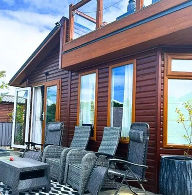 a group of chairs sitting on the porch of a house at Lakeside Lodge - Lakeside Lodge Retreat - Golf & Spa, Gleneagles in Dunning