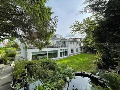 a large white house with a pond in the yard at 2 Bedroom Garden Flat in Bearsden