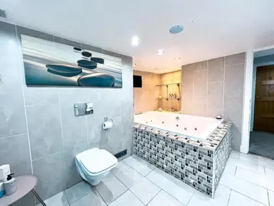 a bathroom with a tub and a toilet and a sink at 2 Bedroom Garden Flat in Bearsden