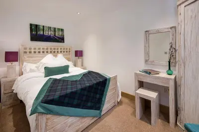 a bedroom with a bed and a table with a mirror at Arrochar House in Tarbet