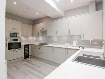 a white kitchen with white cabinets and a sink at Beach House in Stranraer