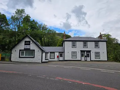 a white building on the side of a street at Lochview Apartment in Tarbet