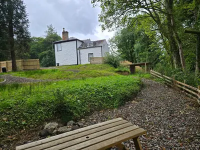 a wooden bench in front of a white house at Lochview Apartment in Tarbet
