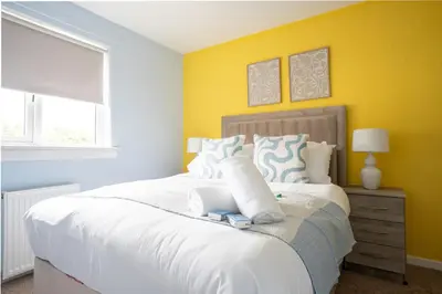 a bedroom with a large white bed with yellow walls at 3 BDR House By Caledonia Luxe Stays Short Lets & Serviced Accommodation Broxburn in Broxburn