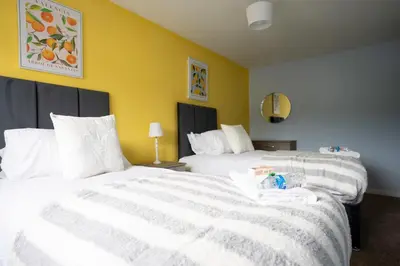 two white beds in a room with yellow walls at 3 BDR House By Caledonia Luxe Stays Short Lets & Serviced Accommodation Broxburn in Broxburn