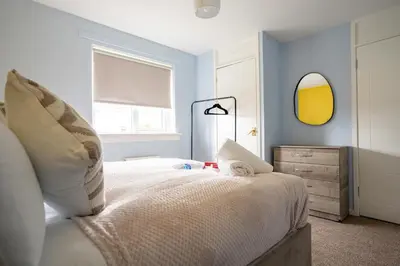 a bedroom with a bed with a mirror and a dresser at 3 BDR House By Caledonia Luxe Stays Short Lets & Serviced Accommodation Broxburn in Broxburn