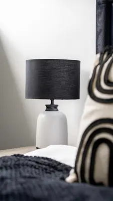 a white lamp sitting on a table next to a bed at Torbrex House in Cumbernauld