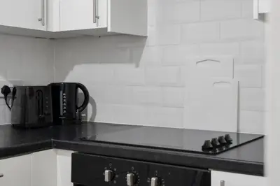 a kitchen with white cabinets and a black stove top oven at Free Parking - Sleeps 6 - 2 Bedrooms - Newly Renovated in Greenock